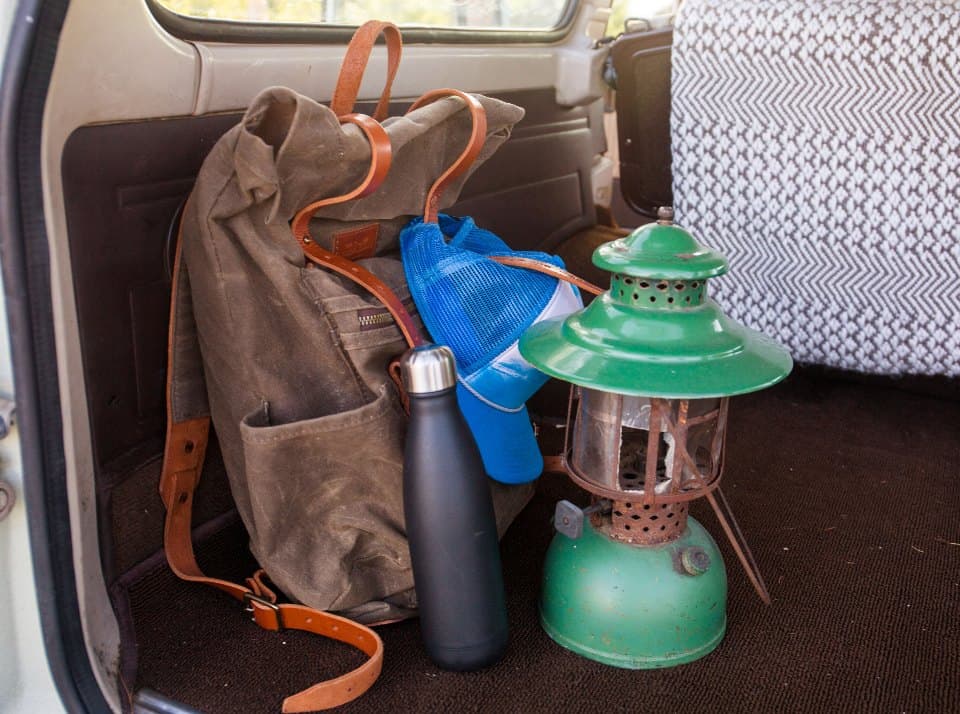 Waxed canvas pack, flask, and lantern packed for a weekend