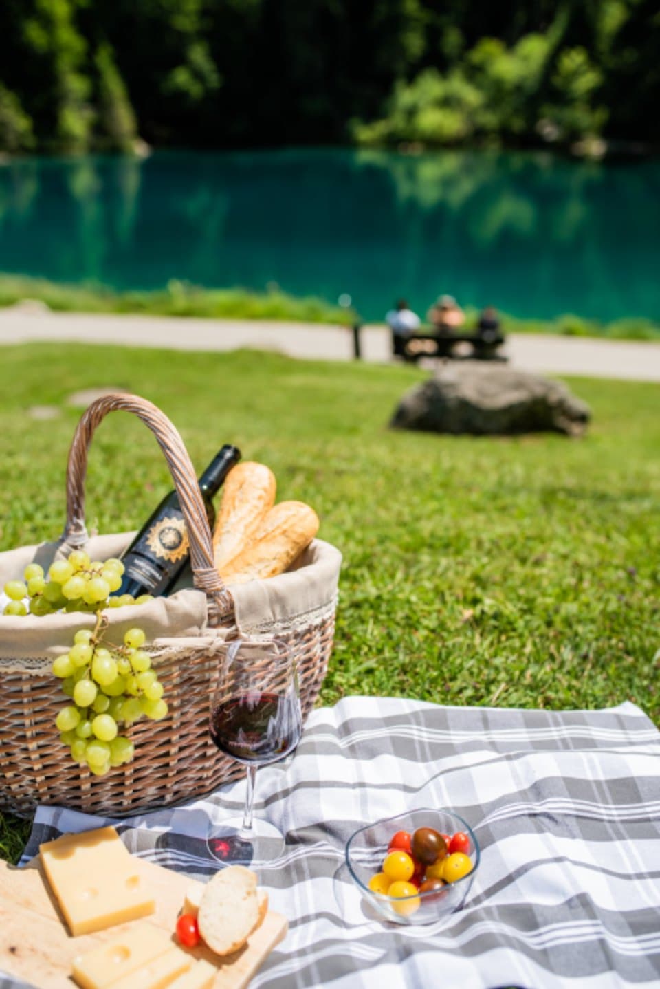 Lakeside picnic with basket, wine, and checkered cloth